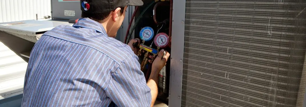 HVAC technician servicing a condenser unit in Flowery Branch