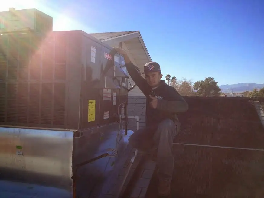 HVAC technician performing AC Tune-Up on a rooftop unit in Flowery Branch